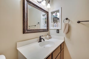 Une salle de bain avec un lavabo blanc, un grand miroir et un porte-serviettes.