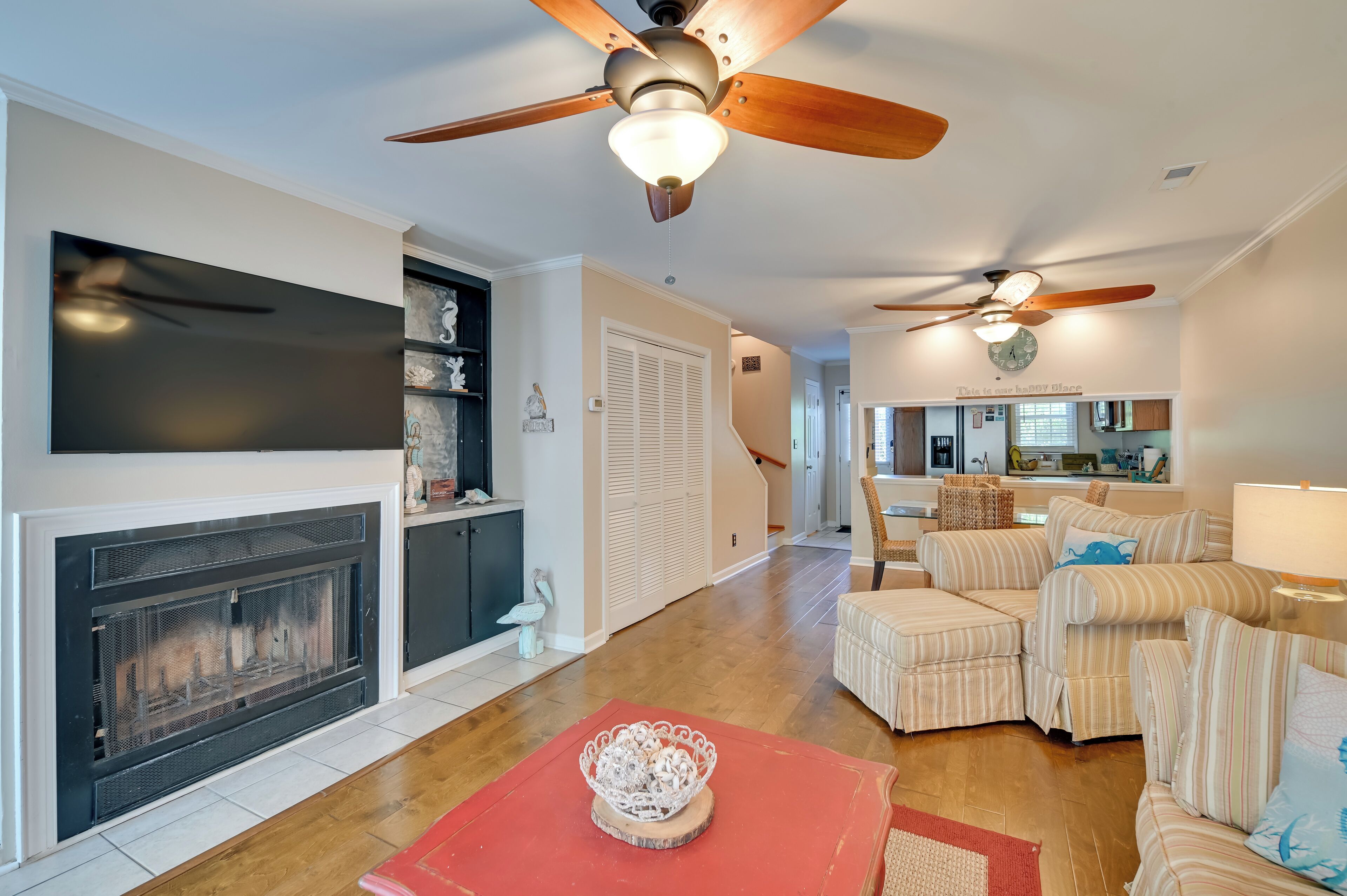 A living room with a fireplace, striped sofas, and ceiling fans.
