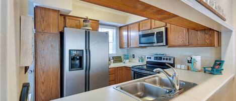 A modern kitchen with wooden cabinets, stainless steel appliances, and a white countertop.