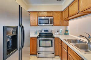 A kitchen with wooden cabinets, a stainless steel refrigerator, a microwave, an oven, and a sink. - Coastal Vacation Rental - 2 Mi to Huntington Beach (Murrells Inlet)