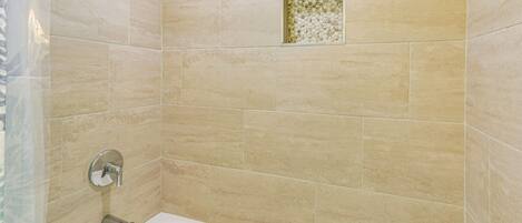 Un baño con azulejos color beige, una bañera y un pequeño azulejo decorativo en la pared.