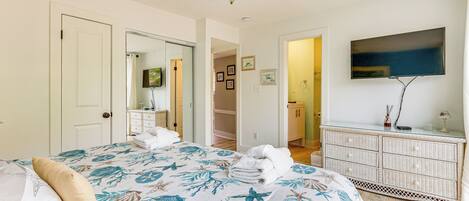 A bedroom with a bed, a dresser, a television, and a ceiling fan.