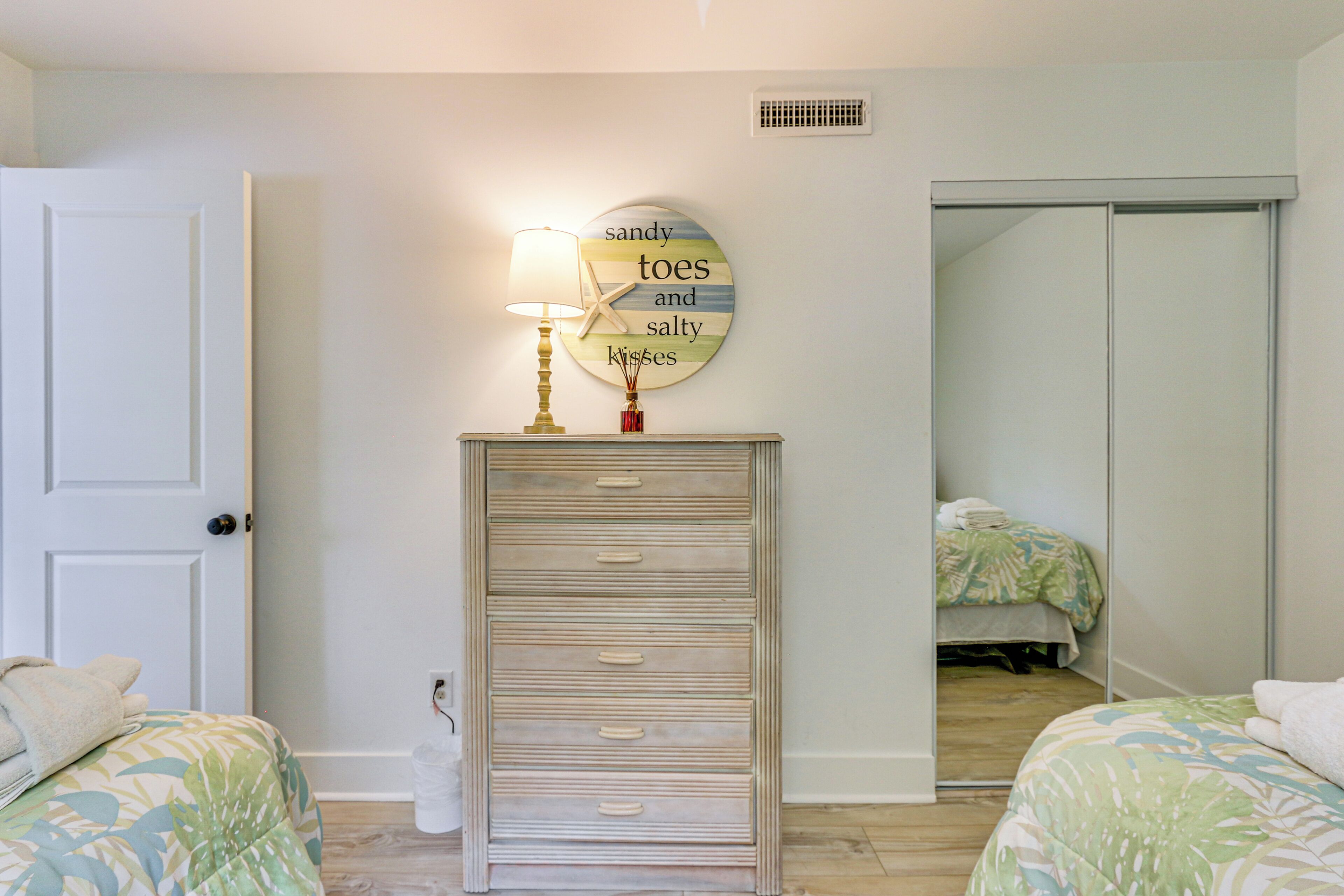 A bedroom with two beds, a dresser, a wall clock, and a mirror.