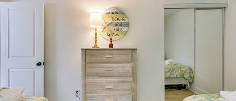 A bedroom with two beds, a dresser, a wall clock, and a mirror.
