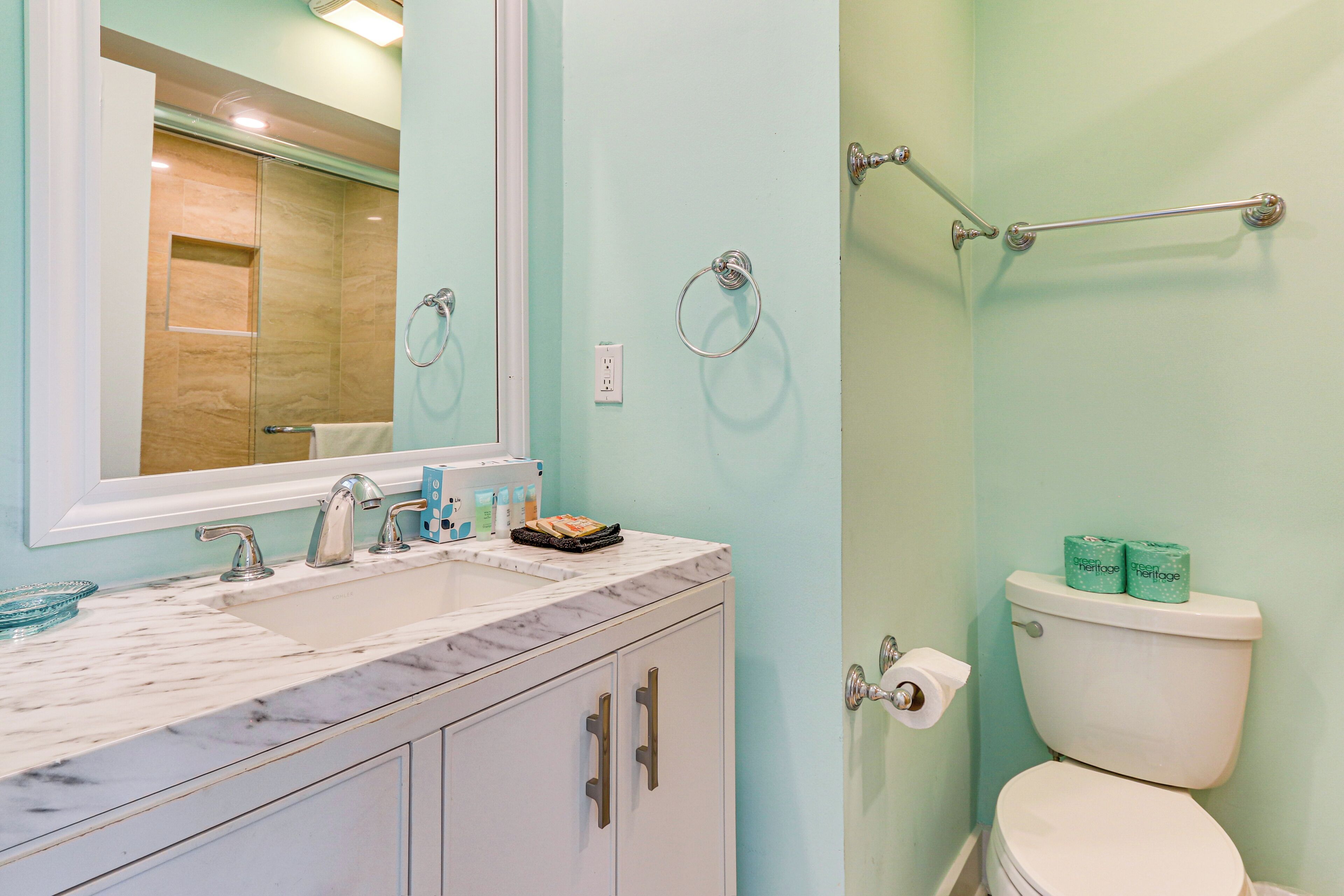 A bathroom with a marble sink, a toilet, and a glass shower enclosure.
