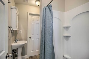 A bathroom with a white sink, a door, and a shower curtain.