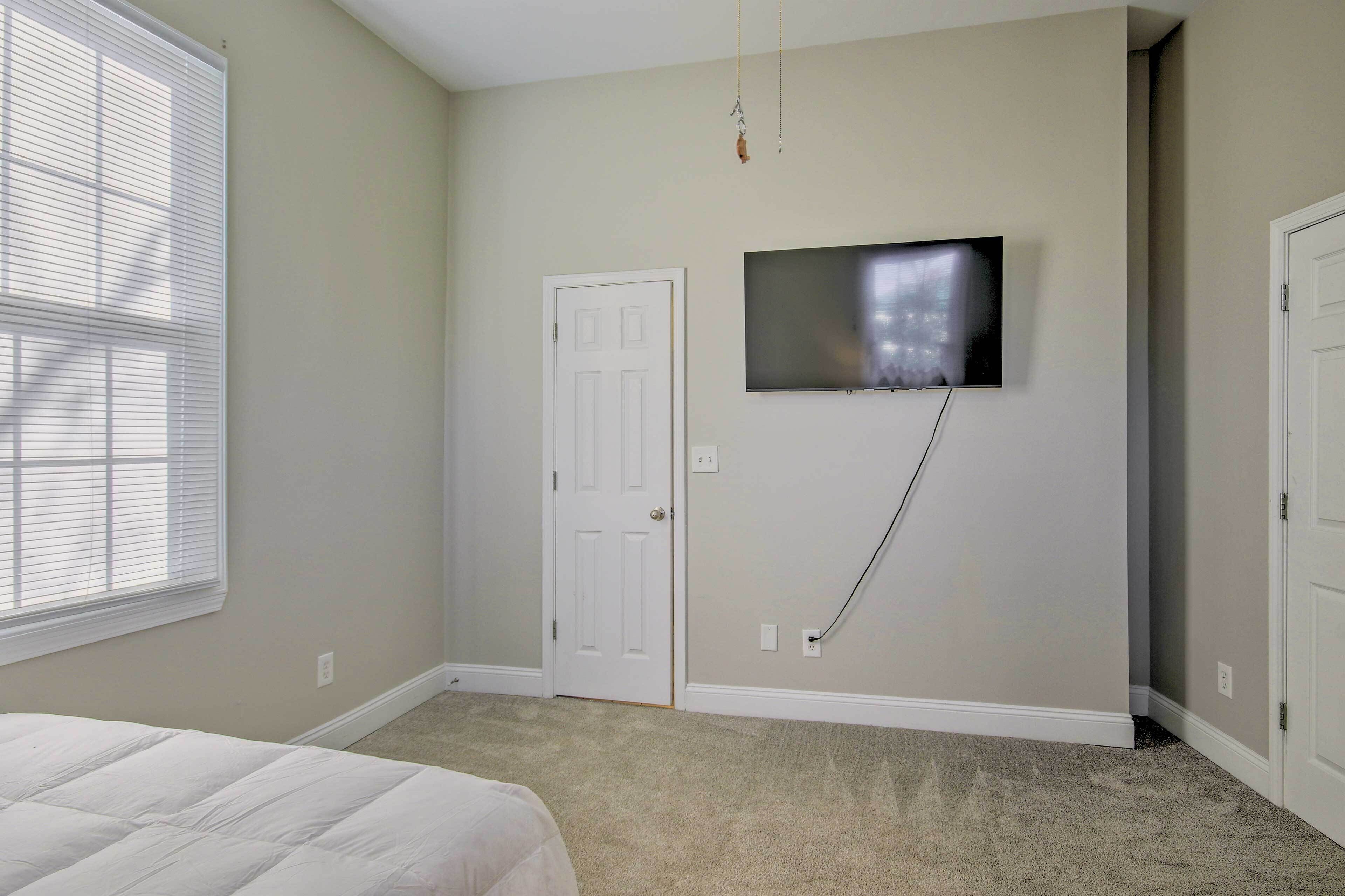 A bedroom with a bed, a TV mounted on the wall, and a door.