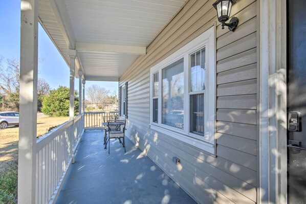 A covered porch with a table and chairs, a door with a lock, and a window with blinds.