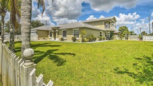 A two-story house with a front lawn, a white picket fence, and a balcony. - Cozy Coastal Retreat w/ Grill < 5 Mi to Beach (Port Orange)