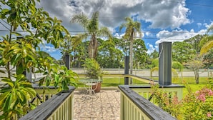 A patio area with a tiled floor, a glass table, and chairs, surrounded by lush greenery and a white picket fence. - Cozy Coastal Retreat w/ Grill < 5 Mi to Beach (Port Orange)