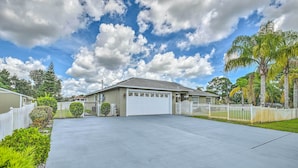 A residential house with a garage, surrounded by a white picket fence, and lush greenery. - Cozy Coastal Retreat w/ Grill < 5 Mi to Beach (Port Orange)