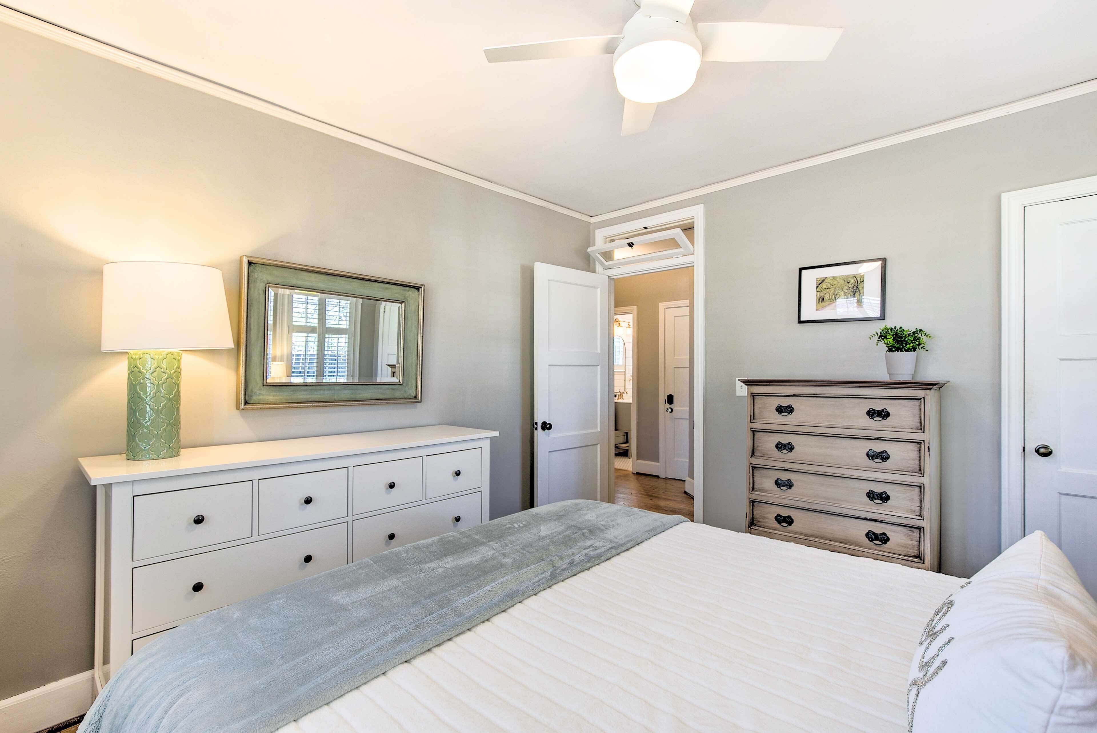 A bedroom with a bed, a dresser, a mirror, a lamp, and a ceiling fan.