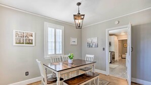 A dining room with a wooden table, white chairs, a bench, and a hanging light fixture. - Columbia Vacation Rental < 2 Mi to University (Columbia)