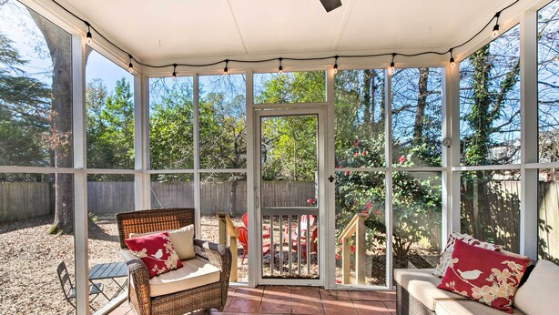 A covered patio with wicker furniture, a cushioned bench, and a view of a backyard with a wooden fence and trees. - Columbia Vacation Rental < 2 Mi to University (Columbia)