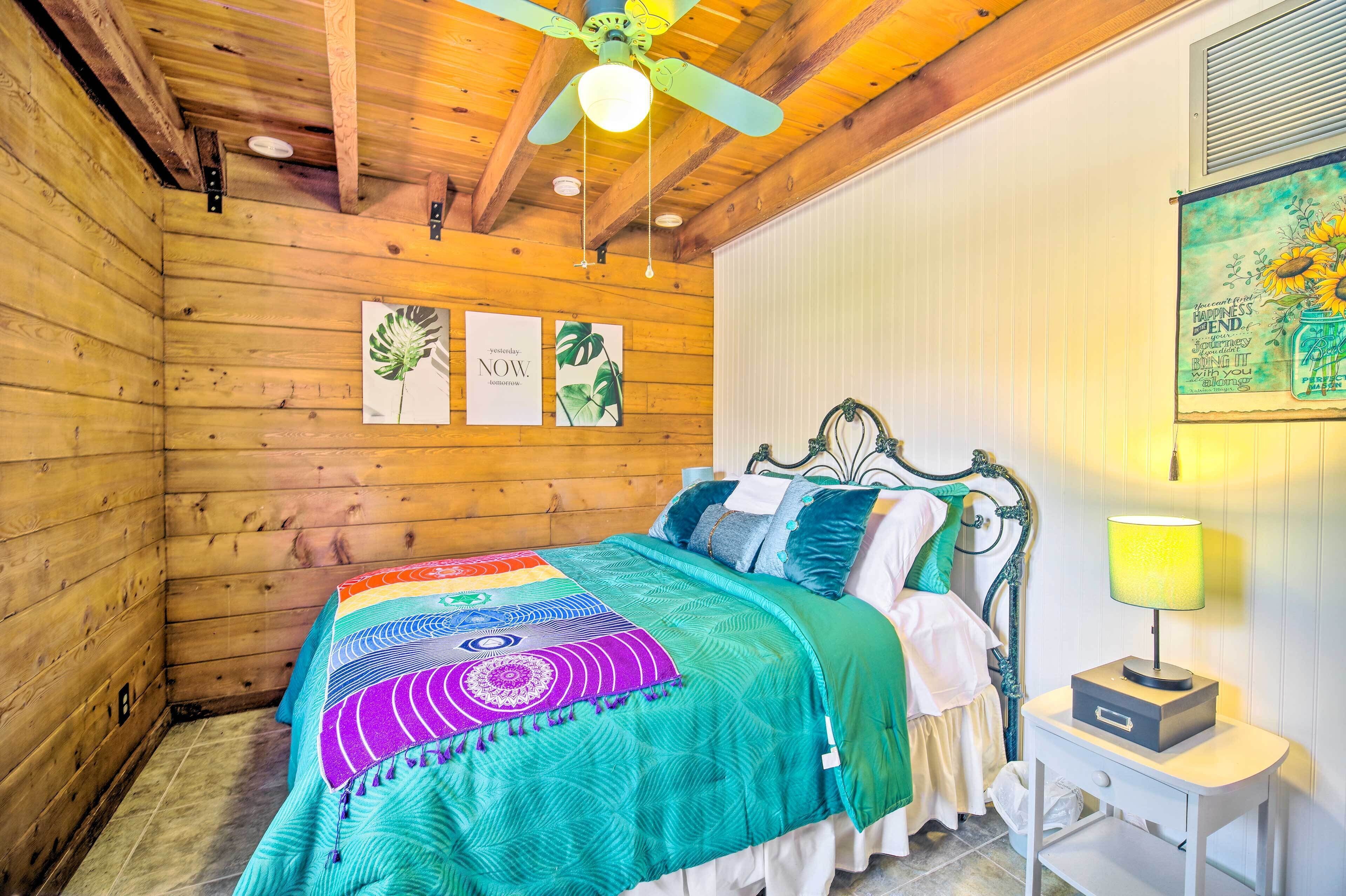 Una habitación de madera con una cama, una mesita de noche y un ventilador de techo.