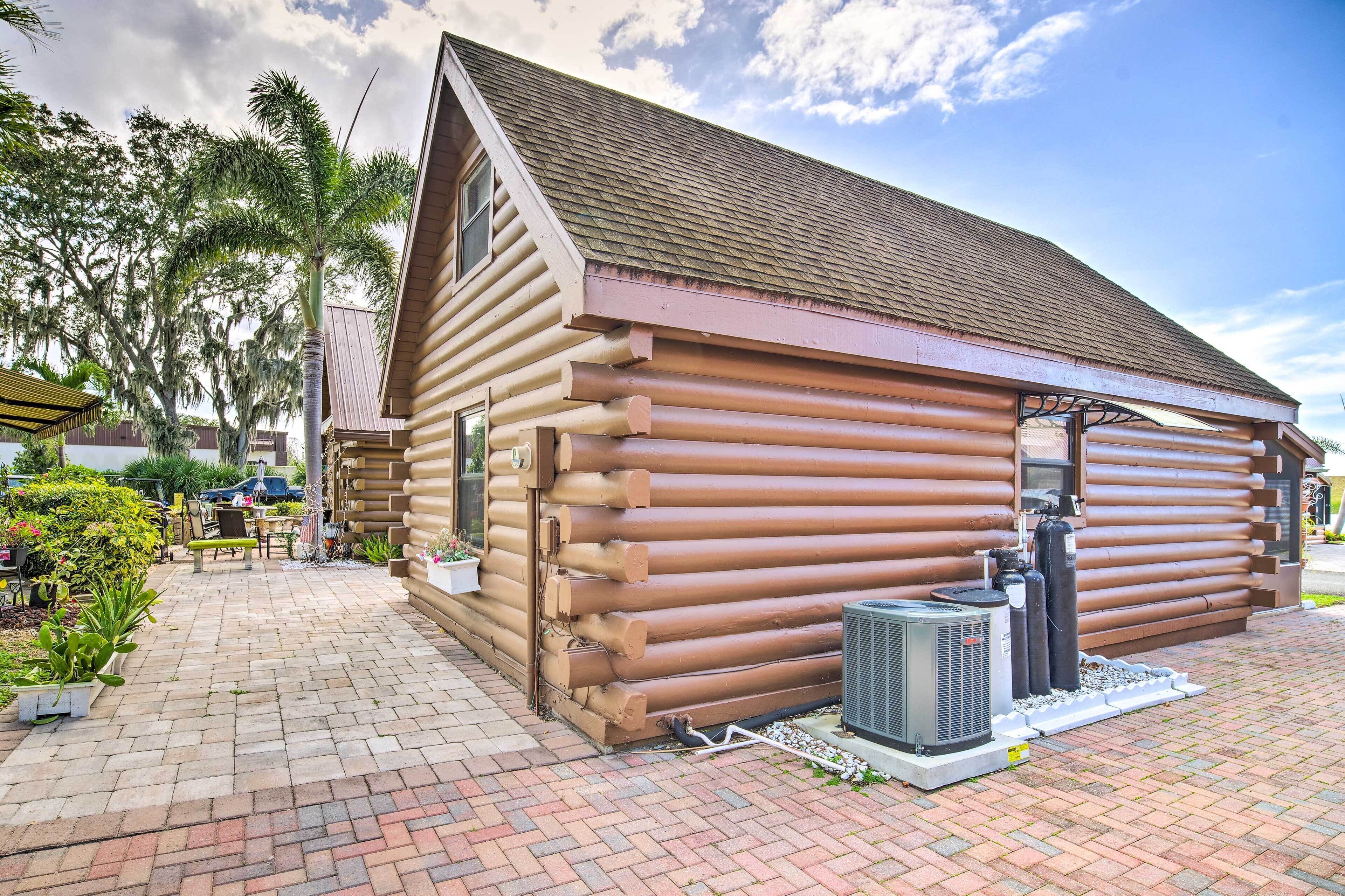 A log cabin with a sloped roof, a brick patio, and outdoor seating.
