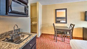 Habitación de hotel compacta con kitchenette, comedor y cama.