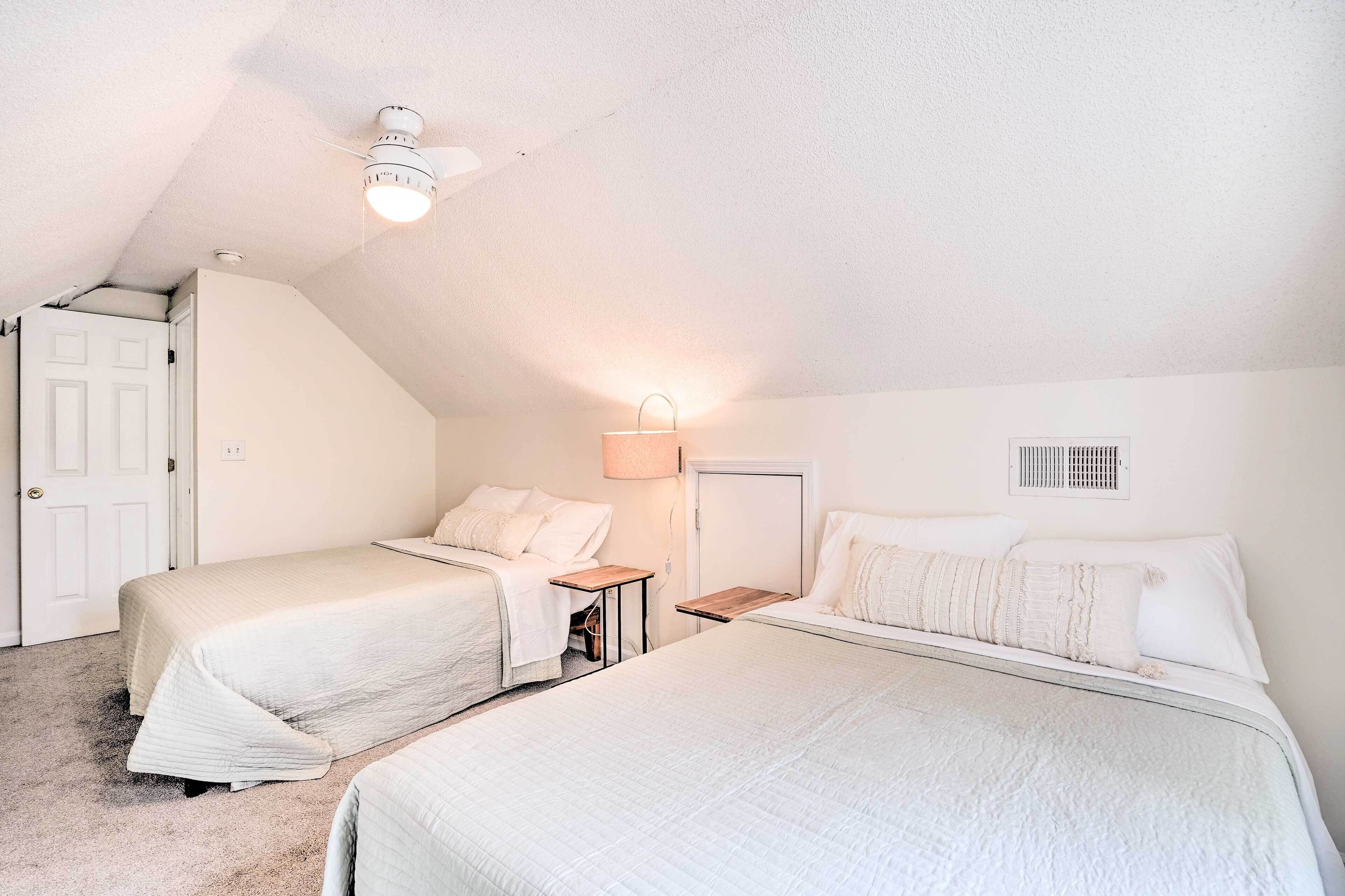 Une chambre avec deux lits, un ventilateur de plafond, une lampe et une porte.