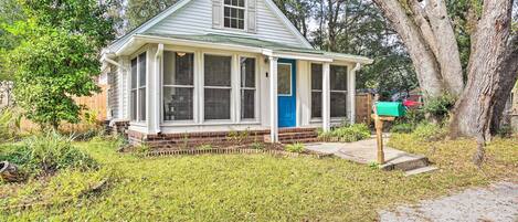 A small, single-story house with a front porch, a blue door, and a mailbox.