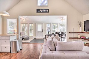 A spacious living area with a large sofa, a dining table, and a kitchen area. - Cozy Home w/ Yard ~ 9 Mi to Dtwn Charleston! (North Charleston)