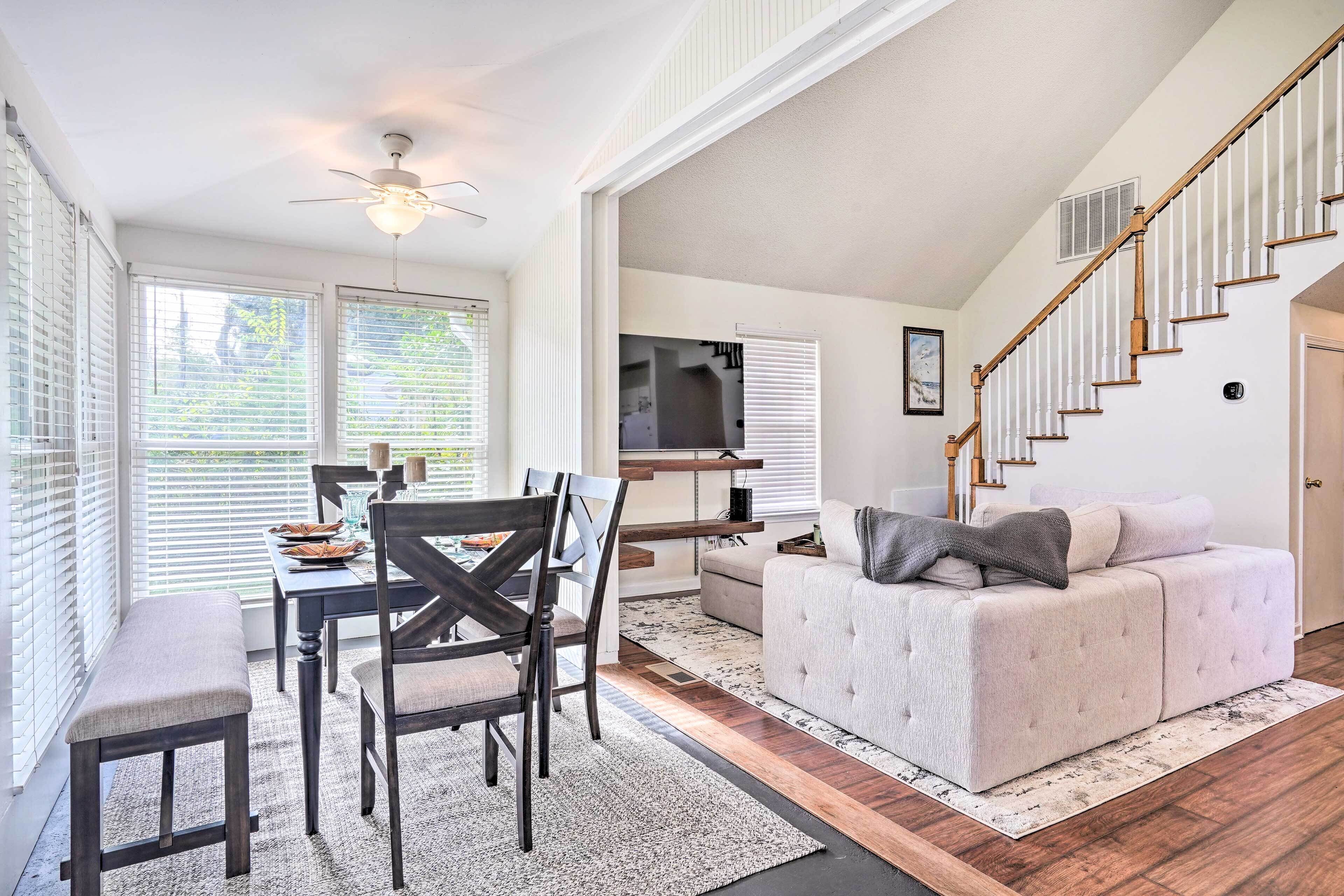 A spacious living area with a dining table, chairs, a sofa, and a staircase.