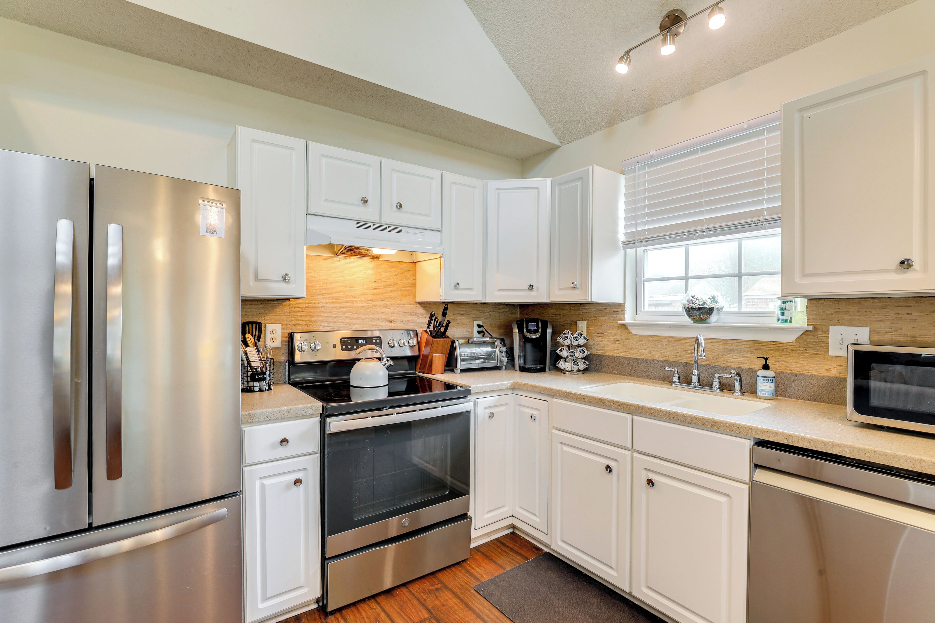 A modern kitchen with stainless steel appliances, white cabinetry, and a built-in oven.