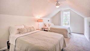 A bedroom with two beds, a ceiling fan, and a window.
