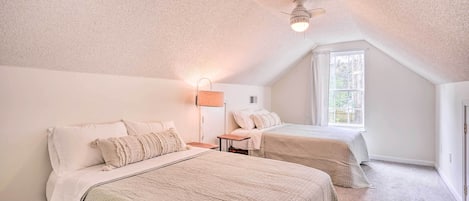 A bedroom with two beds, a ceiling fan, and a window.