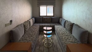 Ein Zimmer mit einer Sofagarnitur, einem kleinen Tisch und einer Deckenleuchte.