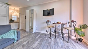 A living room with a grey sofa, a dining table with two chairs, a ceiling fan, and a potted plant. - Cozy Jacksonville Studio - 10 Miles to Downtown! (Jacksonville)