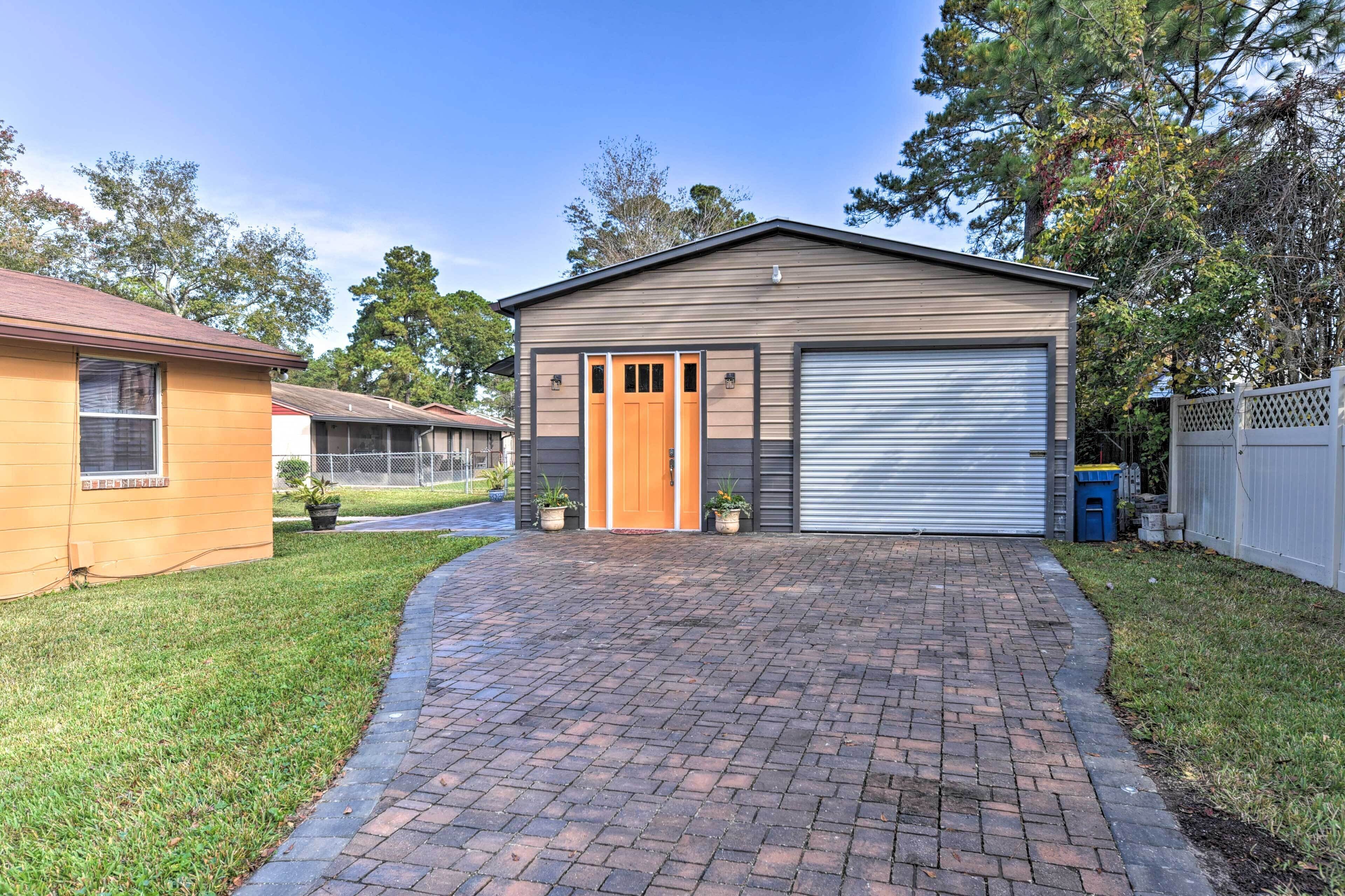 A single-story building with a garage, a brick driveway, and a small lawn area.