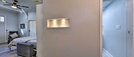 Une chambre à coucher comprenant un lit, un banc, un ventilateur de plafond et un luminaire fixé au mur.