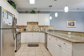 A modern kitchen with white cabinets, granite countertops, stainless steel appliances, and a tiled backsplash. - 3 Mi to Broadway at the Beach: Condo w/ Pool! (Myrtle Beach)