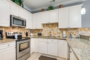 A kitchen with white cabinets, a stainless steel stove, a microwave, and a granite countertop. - 3 Mi to Broadway at the Beach: Condo w/ Pool! (Myrtle Beach)