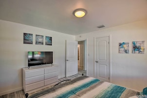 A bedroom with a bed, a TV, a dresser, and artwork on the walls.
