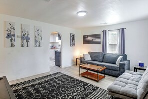 A modern living room with a grey sofa, a wooden coffee table, and a patterned rug.