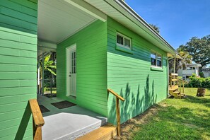 Une maison verte avec un porche, un escalier en bois et une petite fenêtre.