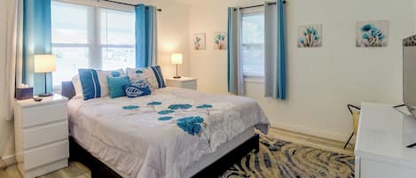 A bedroom with a bed, nightstands, a lamp, and a window with curtains.