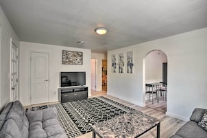 A modern living room with a sofa, a coffee table, a TV, and a patterned rug.