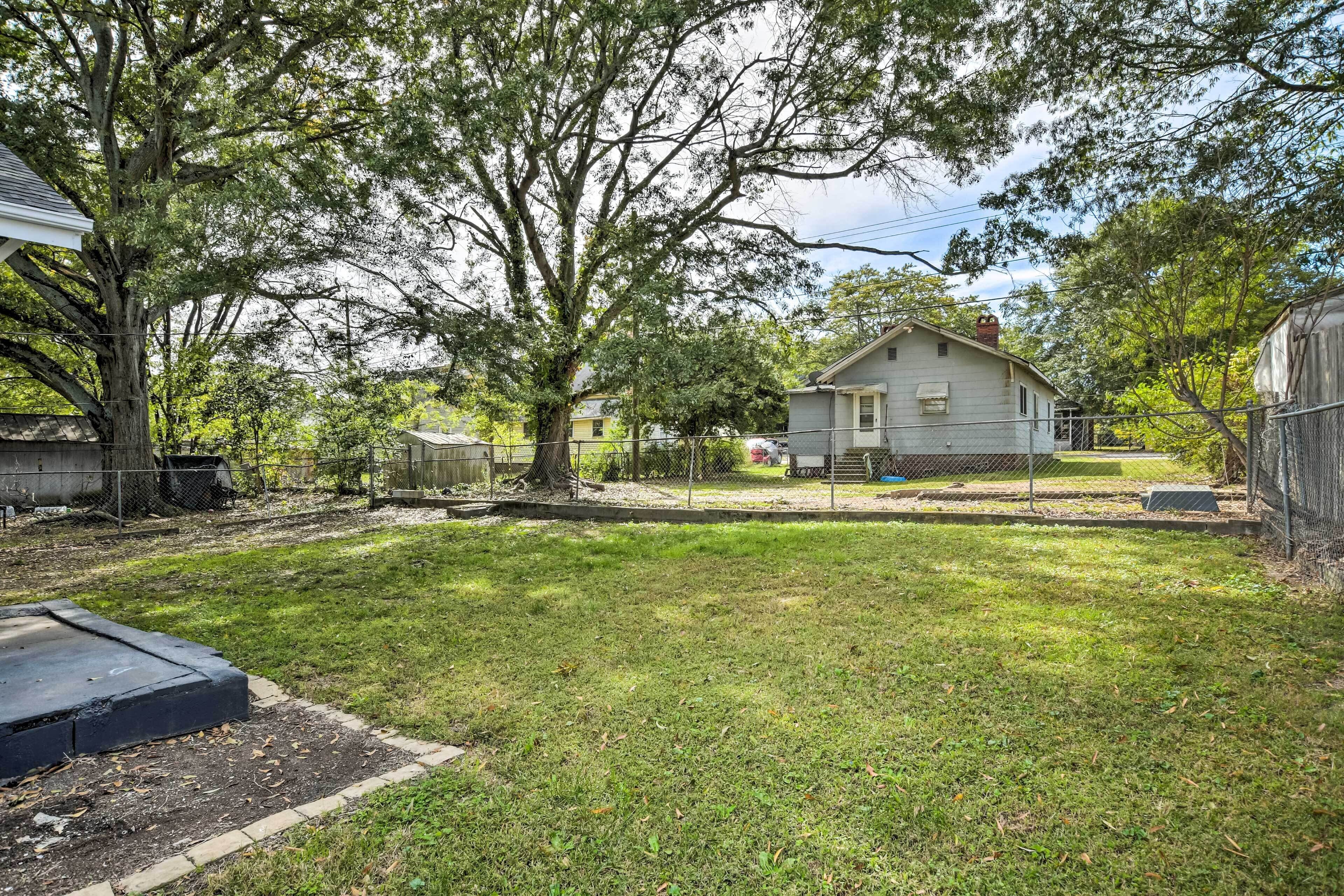A residential backyard with a lawn, a house, and a large tree.