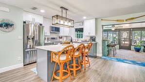 A modern kitchen with a central island, bar stools, and a dining area with a view. - Canal-front Outdoor Oasis: Home in Crystal Water (Crystal River)