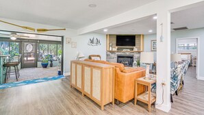 A spacious living area with a wooden sofa, a television, and a fireplace. - Canal-front Outdoor Oasis: Home in Crystal Water (Crystal River)