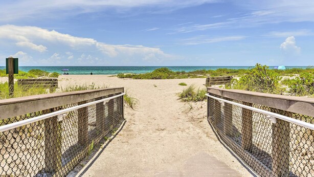 Ein Strandweg, der zum Meer führt, mit blauem Himmel.