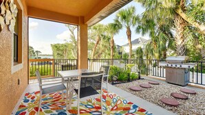 Eine Terrasse im Freien mit Grill, Tisch und Stühlen sowie einem bunten Teppich.