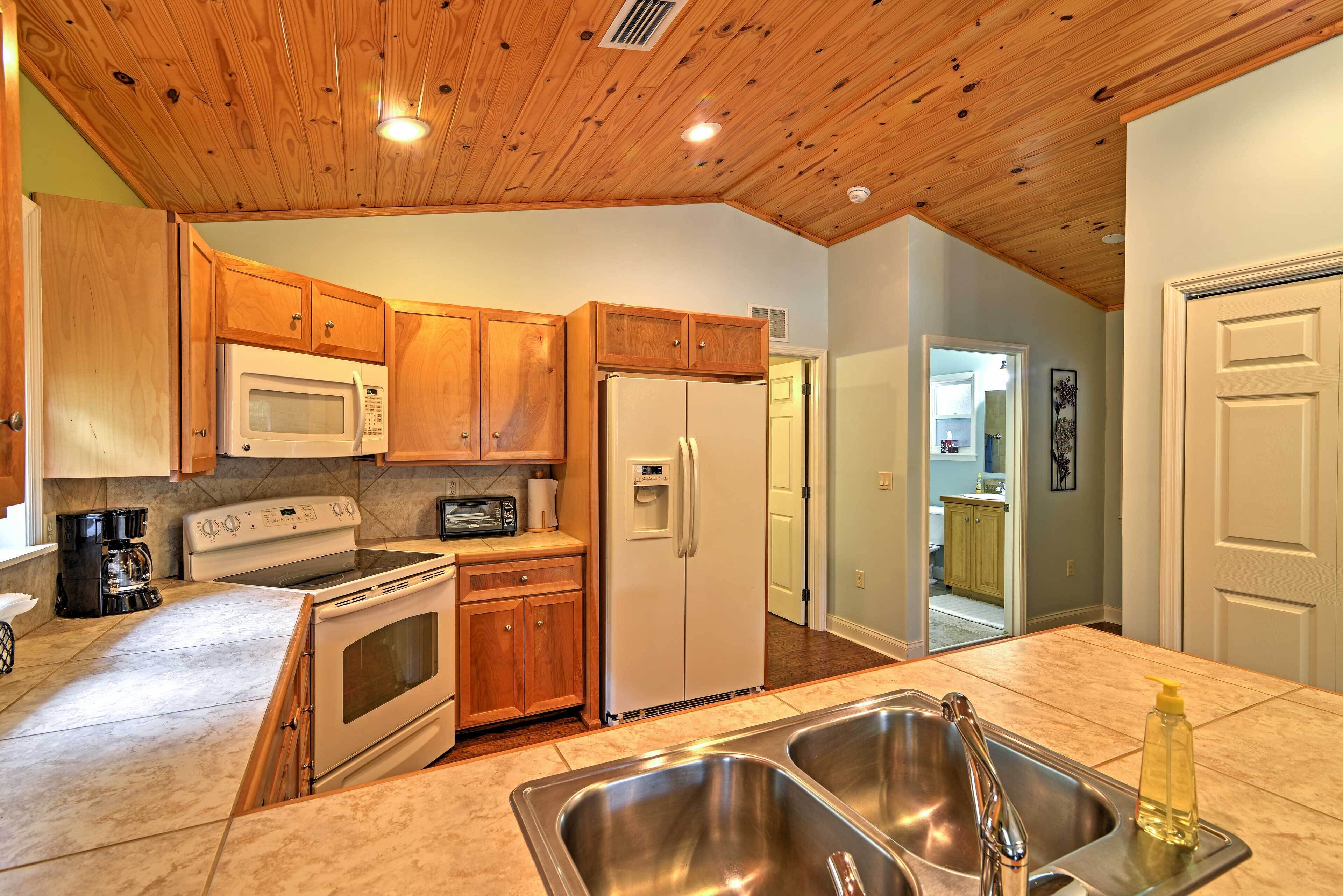 A kitchen with wooden cabinets, a microwave, a stove, a refrigerator, and a double sink.