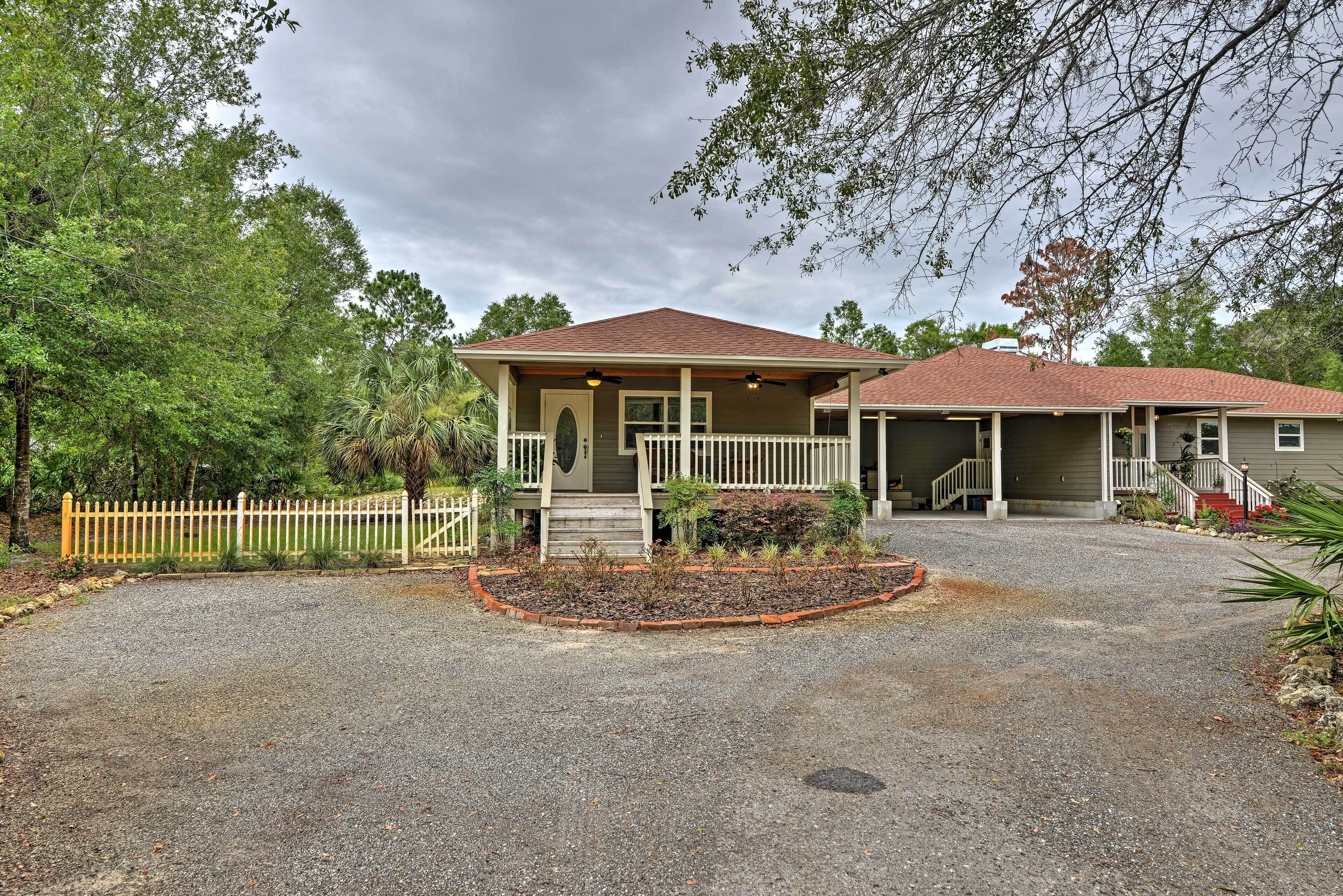 A two-story house with a covered porch and a gravel driveway.