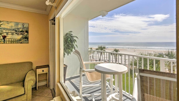 A balcony with a view of the beach, a sofa, a small table, and a potted plant. - Daytona Beach Studio w/ Oceanfront Balcony & Pool! (Daytona Beach)