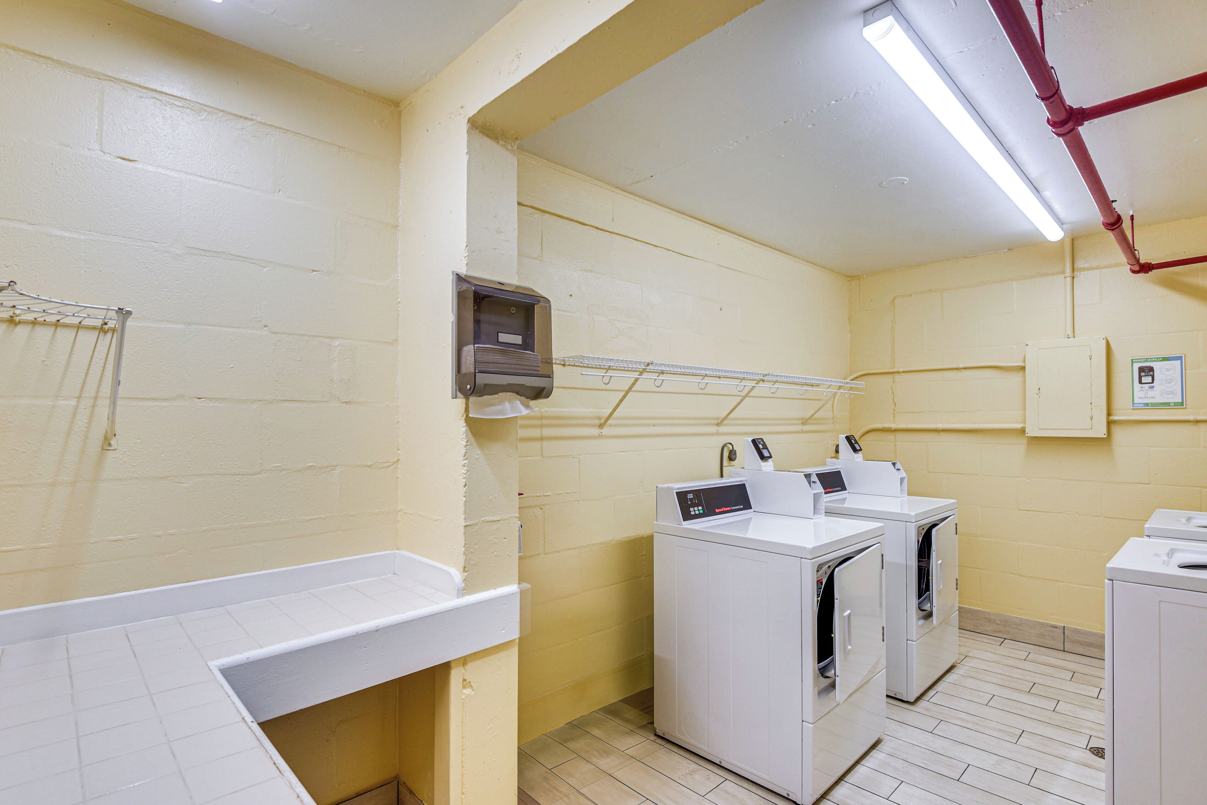 A laundry room with white appliances, a drying rack, and a utility cabinet.