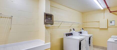 A laundry room with white appliances, a drying rack, and a utility cabinet.