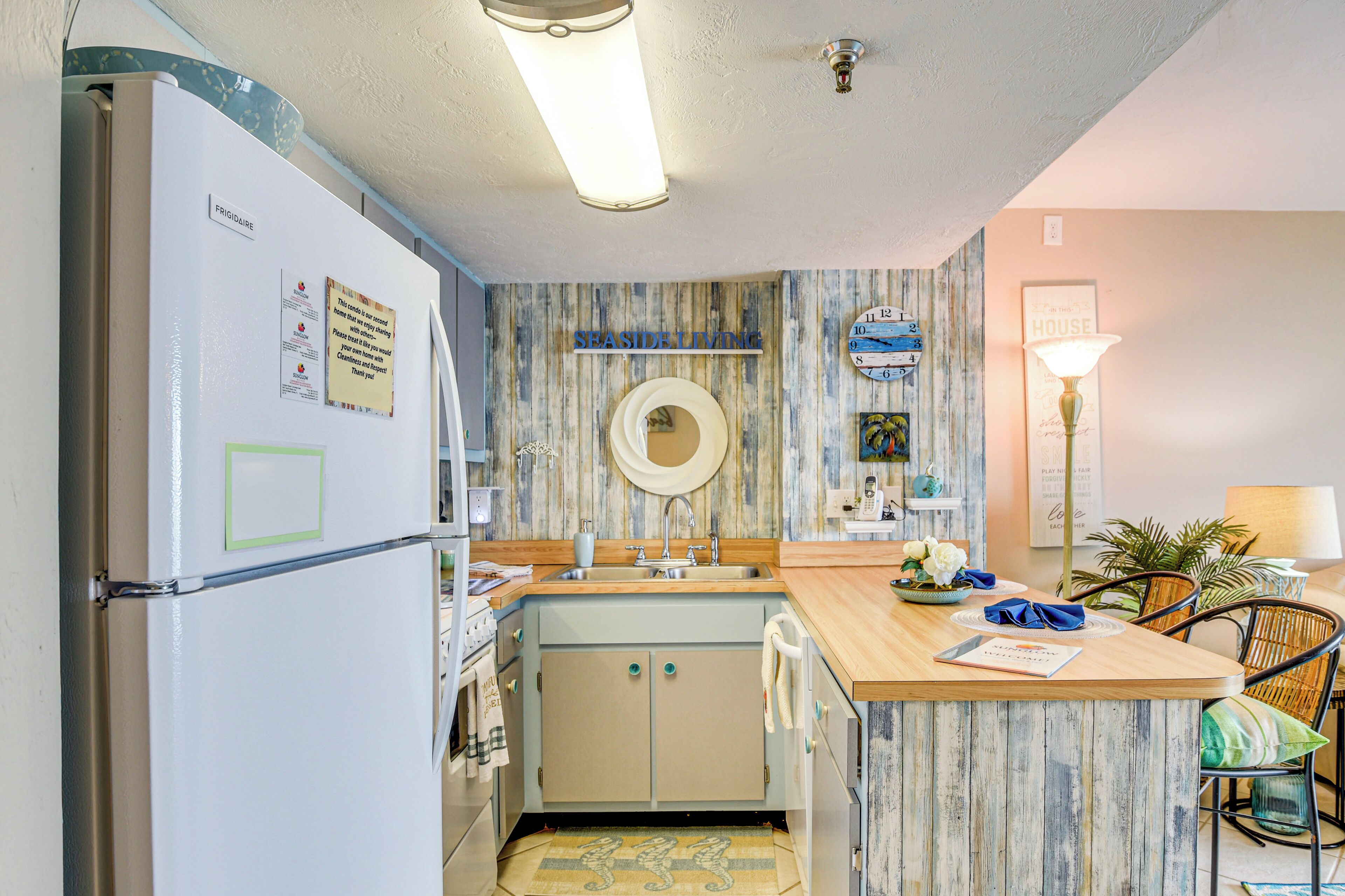 A compact kitchen with a refrigerator, sink, and wooden countertop.